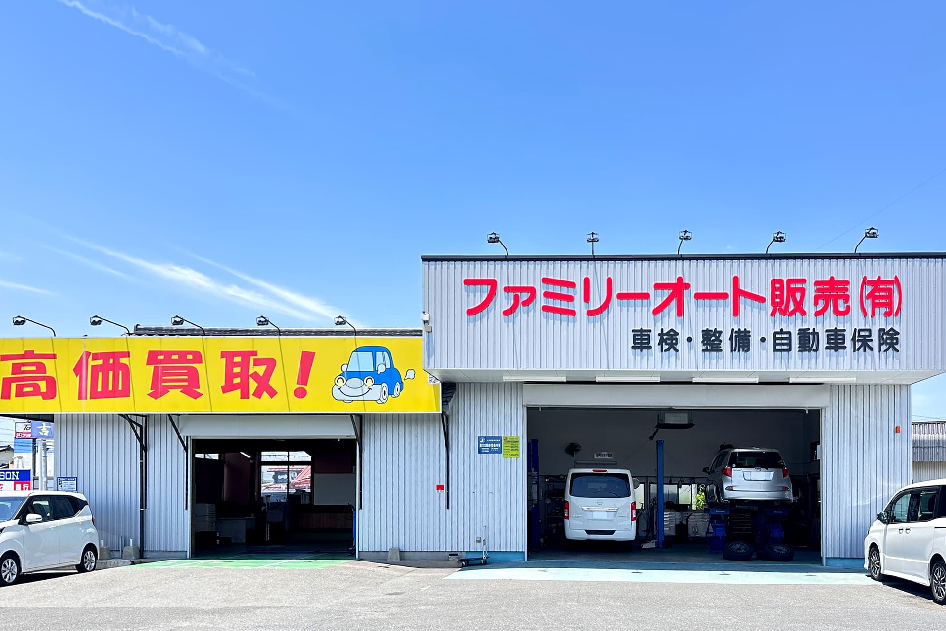 ファミリーオート販売の外観。整備工場内で車両がリフトアップされている。